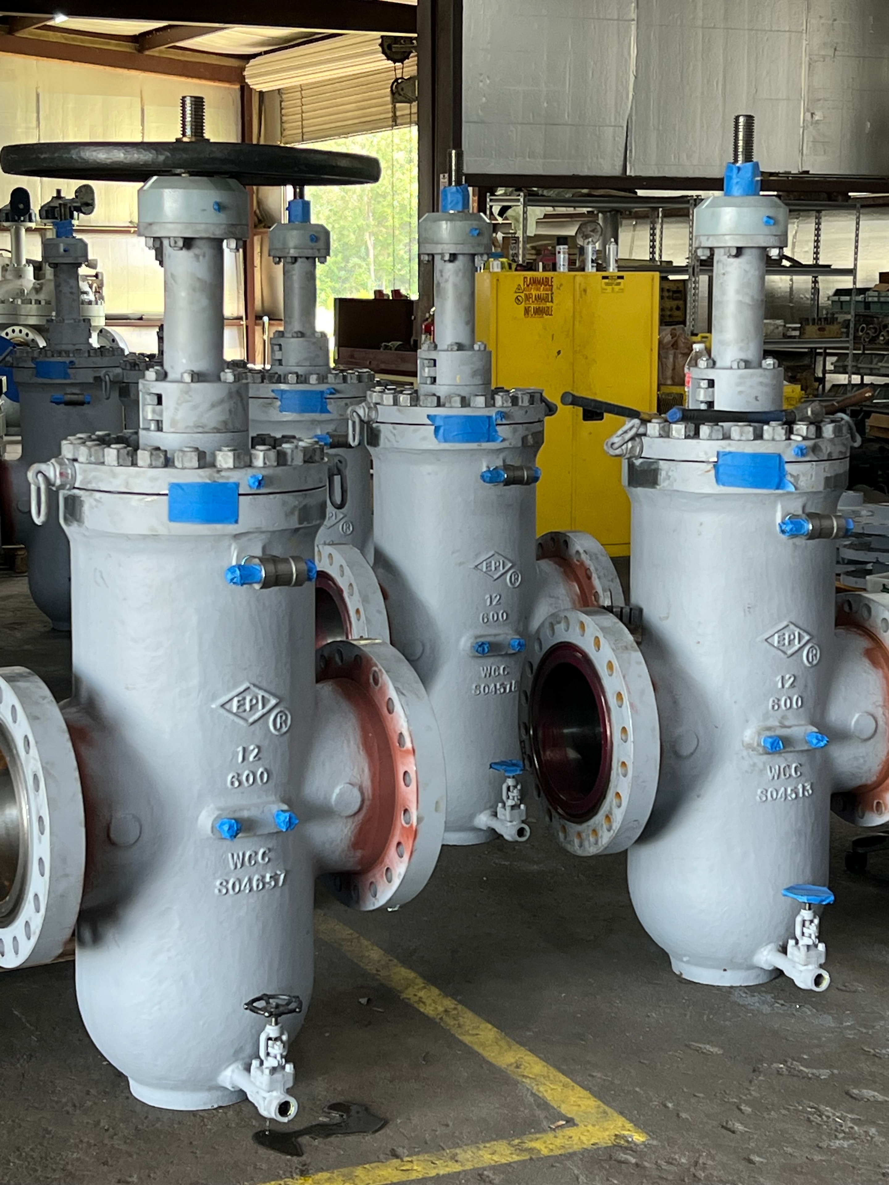 Row of EPI 12 inch 600 class gate valves with blue caps in workshop
